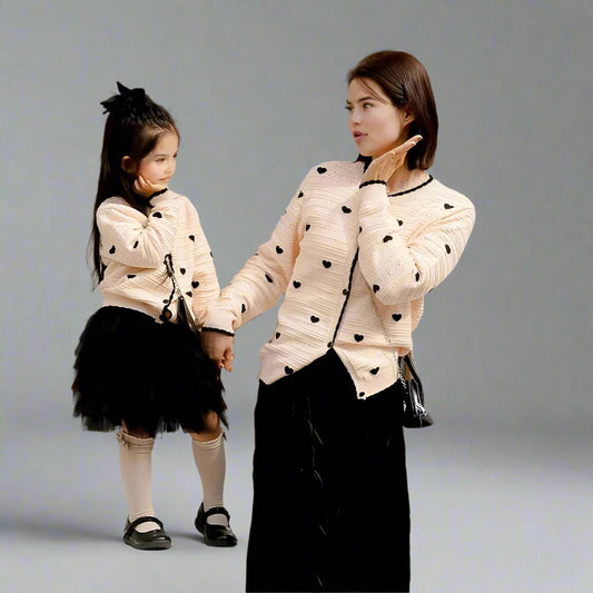 Mother and daughter wearing matching beige cardigans with black hearts and trim