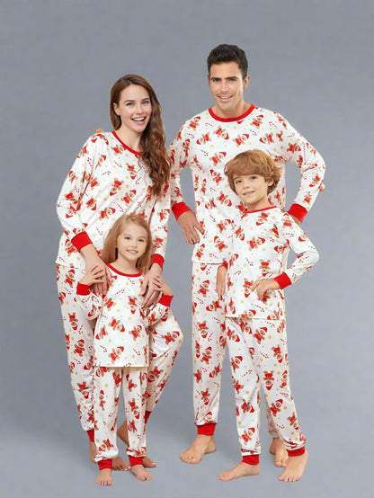 Family wearing matching Christmas pajamas with Santa and reindeer design on white background