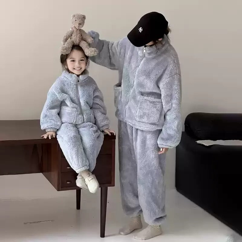 Mother and child wearing matching blue fuzzy loungewear sets, standing indoors and holding hands