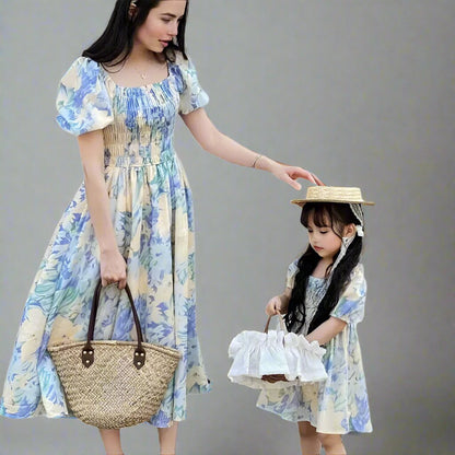 Mother and daughter in matching blue floral dresses with puff sleeves, perfect for summer