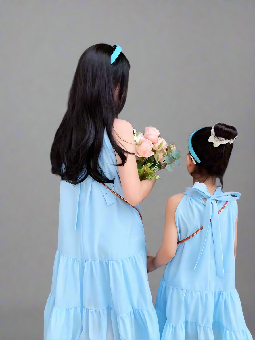 Mom and daughter twirling in light blue matching dresses for summer family outing