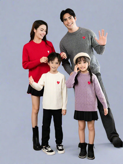 Man and woman wearing matching cable knit sweaters with heart patches in red and grey, perfect for couples