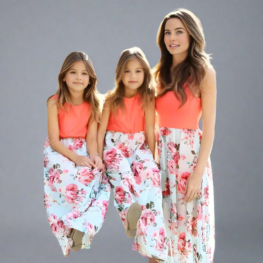 Mother and daughters wearing matching coral orange and floral maxi dresses, perfect for summer