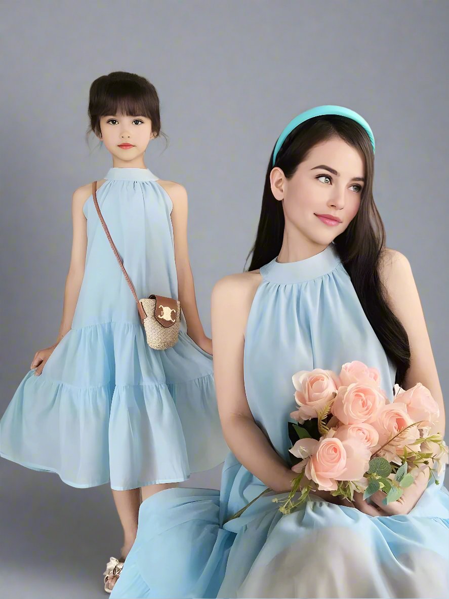 Mother and daughter in coordinated blue dresses, dancing outside a cozy cafe.