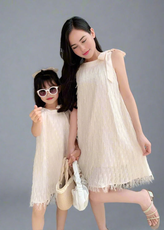 Mother and daughter in matching white fringe dresses holding flowers