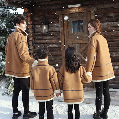 Family coordinated in brown shearling winter coats and black pants, posing together in a festive snowy environment