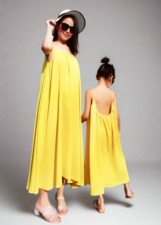 Mother and daughter in matching yellow sundresses at the beach