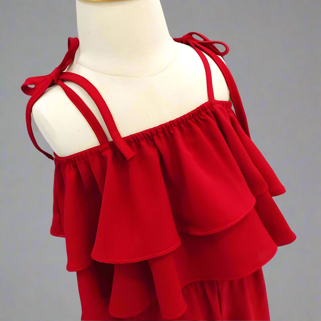 Little girls' red jumpsuit on display, featuring ruffled detailing for a fashionable look